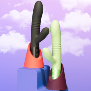 Two elegantly designed dual-stimulation vibrators, one in matte black and the other in pastel green, displayed against a dreamy lavender sky with soft clouds, symbolizing luxury and pleasure.