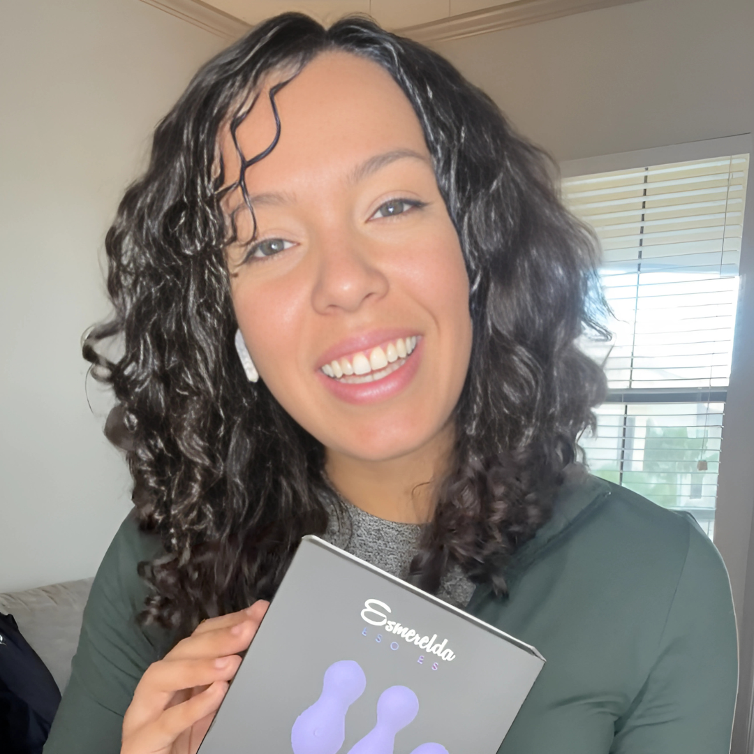 Smiling woman holding the Esmerelda Eve Set box, which contains three purple Kegel toys.
