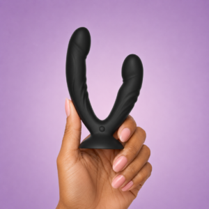 Black Bad Pony dual-ended vibrator with suction base held against a lavender background.